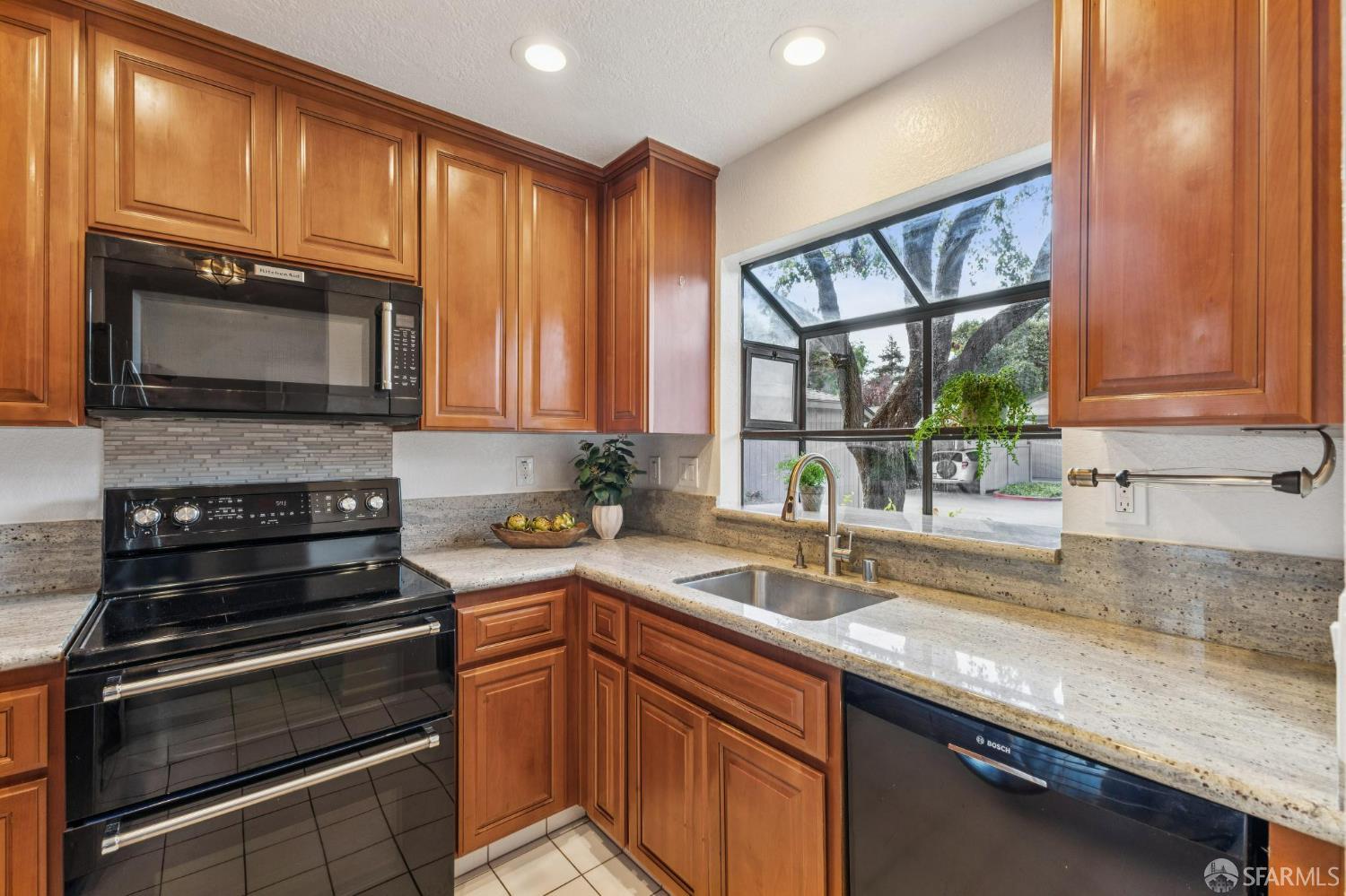 36931 Newark Boulevard, Unit E Newark, CA 94560 - Photo 3 of 37 a kitchen with granite countertop wooden cabinets stainless steel appliances and a window