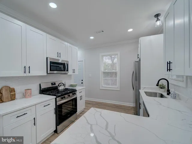 a kitchen with granite countertop a stove a sink and a microwave