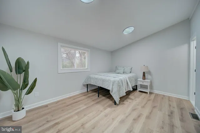 a bedroom with a bed plant and wooden floor
