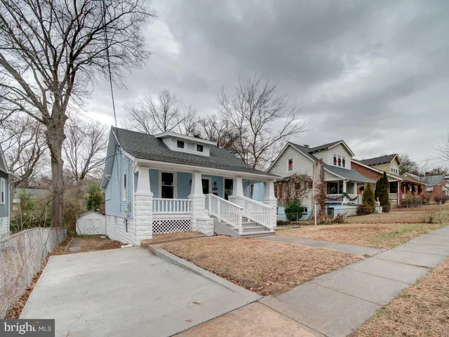 a front view of a house with a yard and large trees