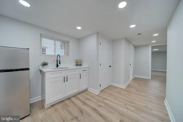 a view of an empty room with wooden floor and a sink