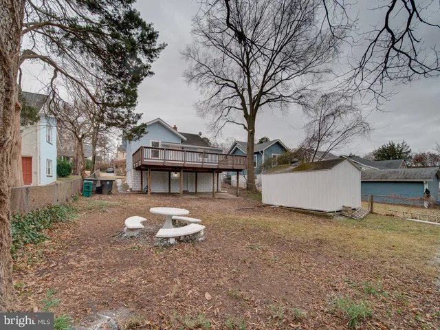 a view of a white house that has a small yard and large trees