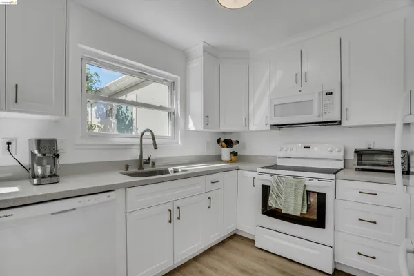 a kitchen with white cabinets and appliances