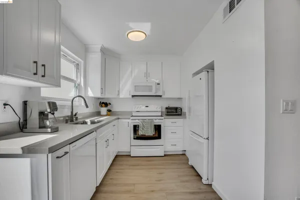 a kitchen with white cabinets sink and white appliances