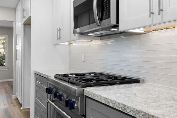 a kitchen with granite countertop a stove and a microwave