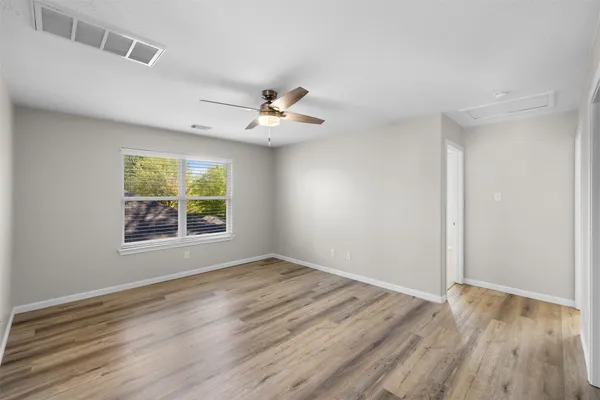 a view of an empty room with wooden floor and a window