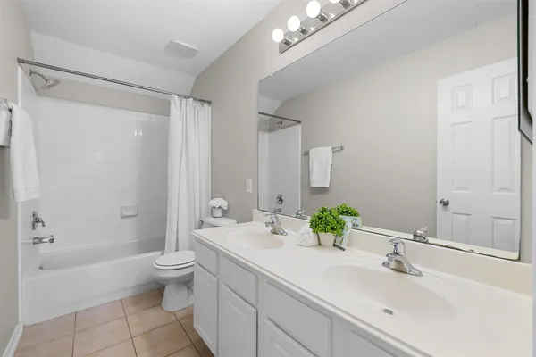 a bathroom with a double vanity sink toilet and shower