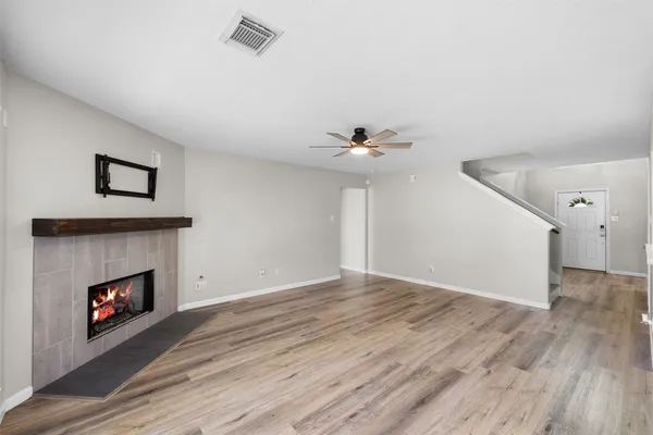 a view of an empty room with wooden floor and a fireplace