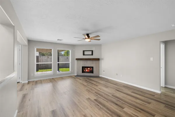 an empty room with windows a fireplace and wooden floor