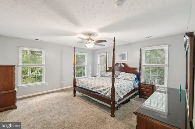 a bed sitting in a spacious bedroom next to a window