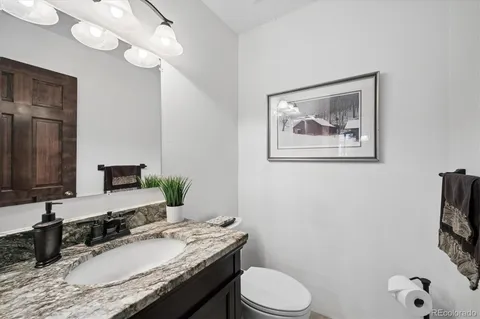 a bathroom with a granite countertop toilet sink and mirror