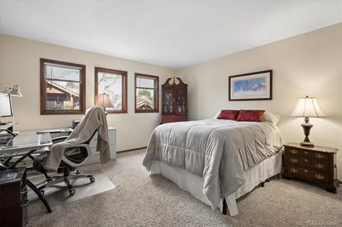 a spacious bedroom with a bed a desk and painting on the wall