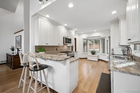 a view of a kitchen with kitchen island granite countertop wooden floor and stainless steel appliances