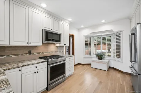 a kitchen with granite countertop a stove a sink and a refrigerator
