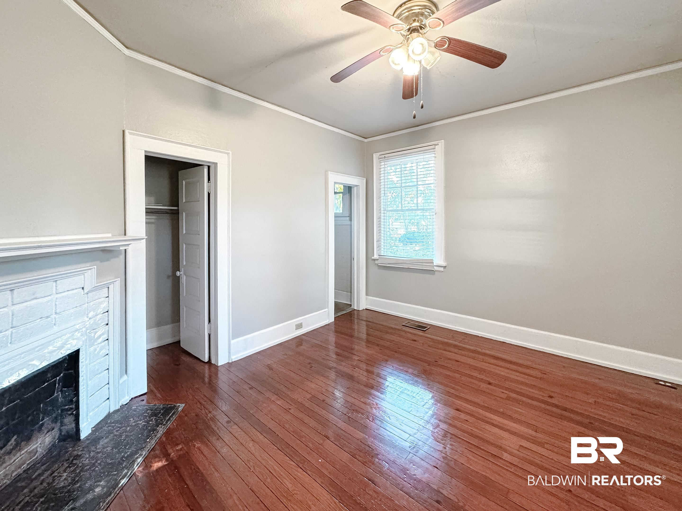 206 1st Street Mobile, AL 36611 - Photo 17 of 26 Unfurnished bedroom featuring ornamental molding, a fireplace, dark wood-style floors, a ceiling fan, and a walk in closet
