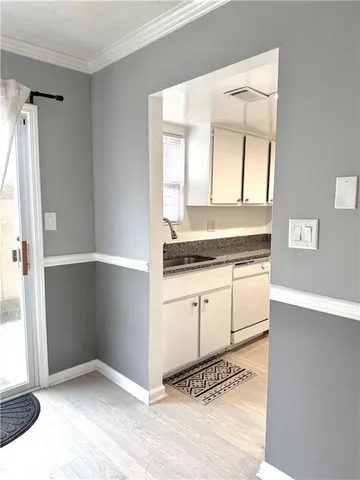 a view of a kitchen with white cabinets and window