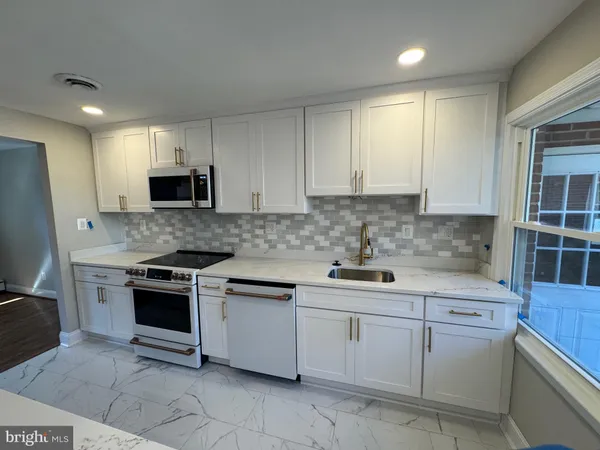 a kitchen with white cabinets appliances and sink