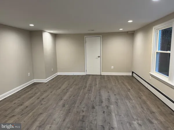a view of an empty room with wooden floor and window