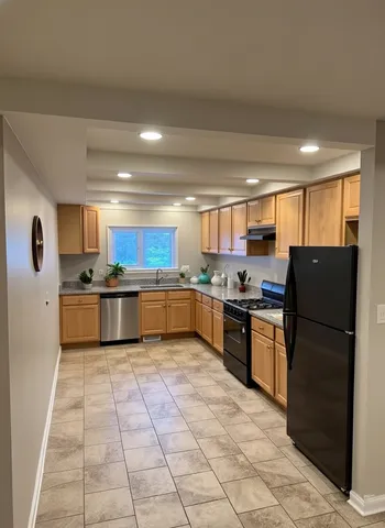 a large kitchen with granite countertop a large counter top stainless steel appliances and cabinets