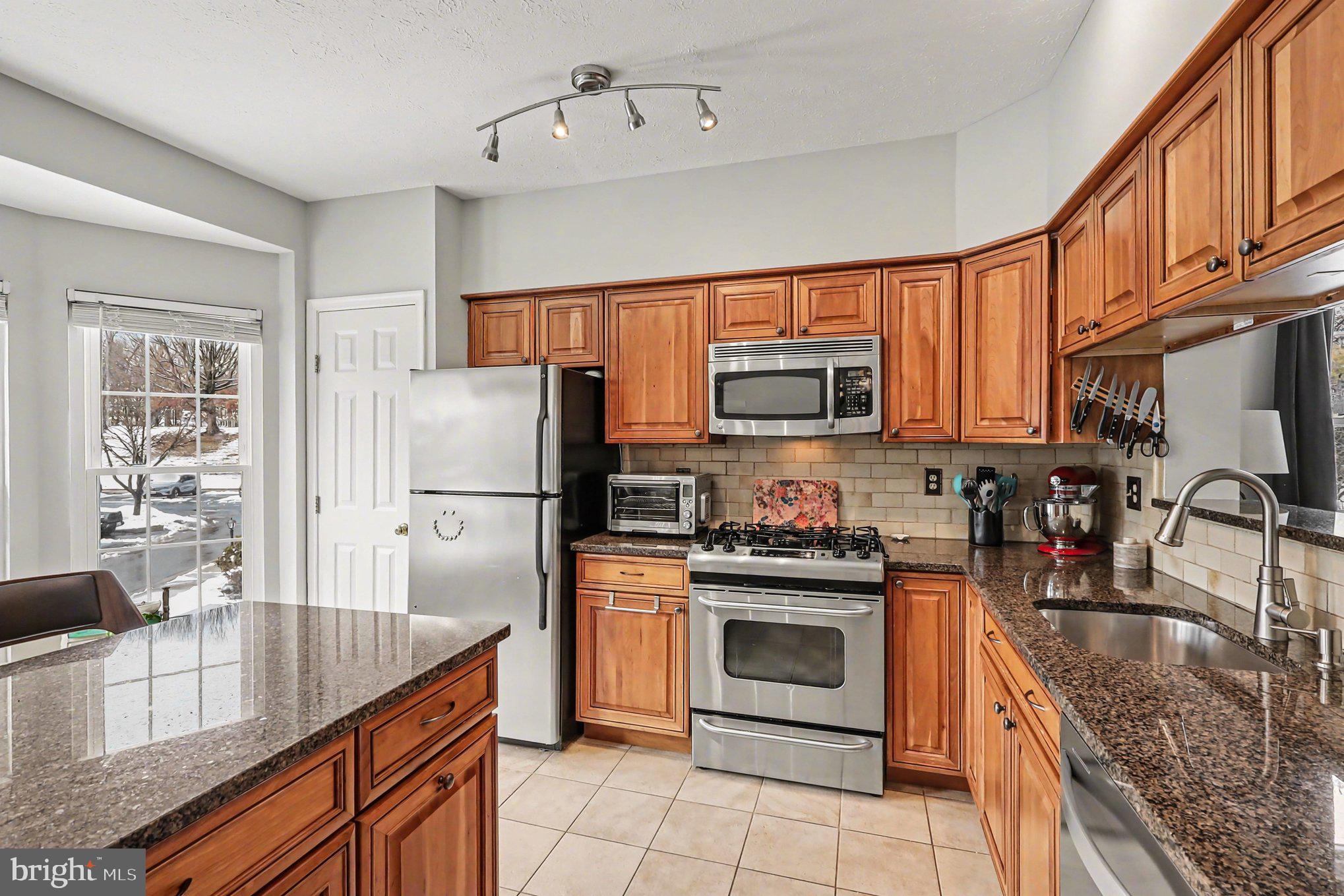 12607 Granite Ridge Drive North Potomac, MD 20878 - Photo 10 of 35 a kitchen with stainless steel appliances granite countertop a stove a sink dishwasher a refrigerator and a microwave