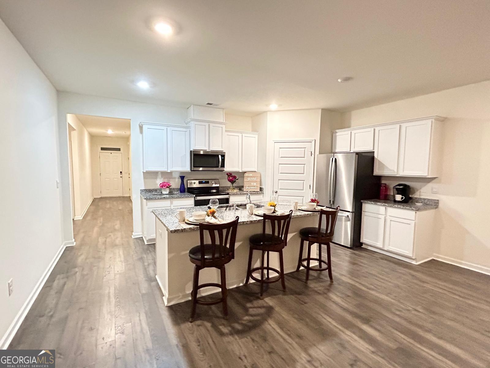 215 Barnyard Way Perry, GA 31069 - Photo 15 of 29 a kitchen with stainless steel appliances a dining table chairs a refrigerator and cabinets