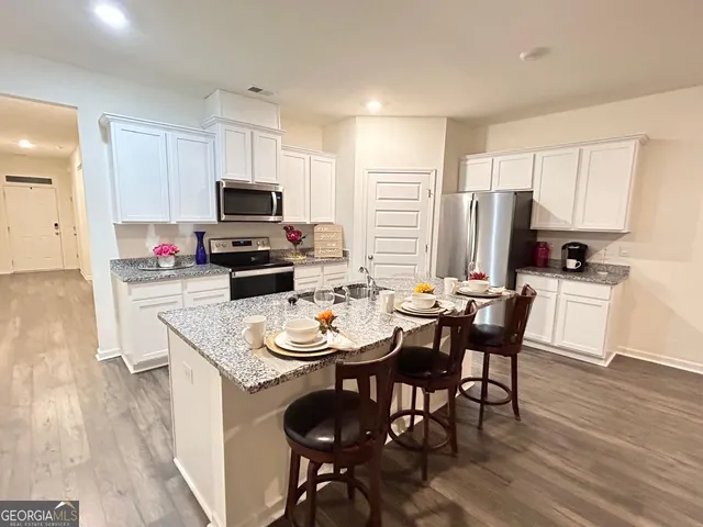 a kitchen with stainless steel appliances a dining table chairs a refrigerator and cabinets