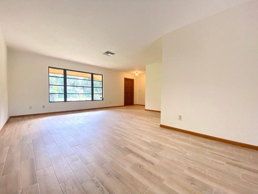 5585 Pennock Point Road Jupiter, FL 33458 - Photo 4 of 19 an empty room with wooden floor and windows