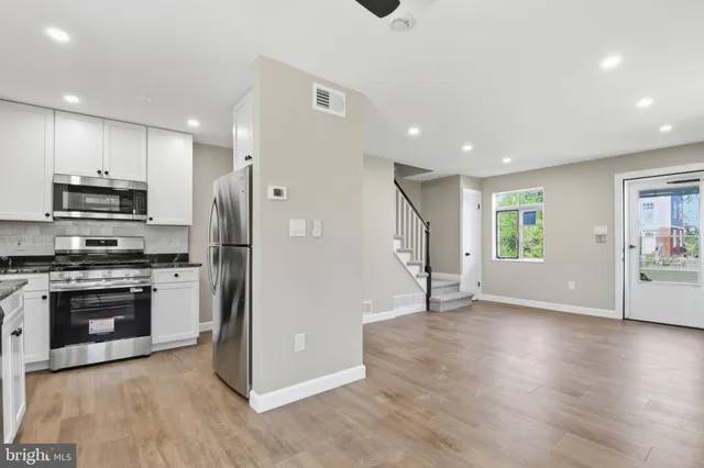 a view of kitchen with stainless steel appliances granite countertop a refrigerator oven a sink and a stove with wooden floor