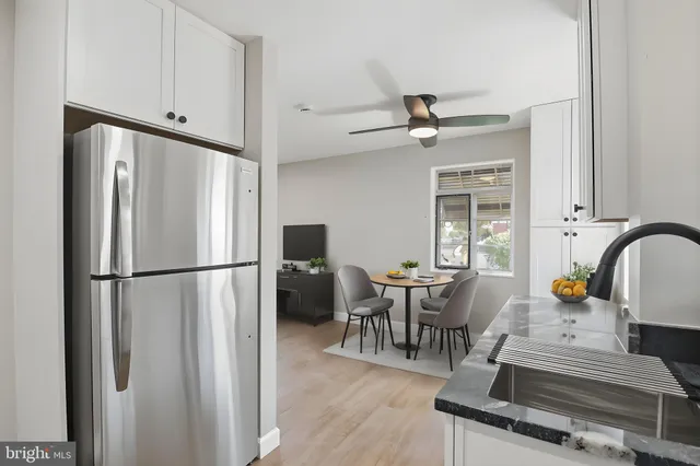 a kitchen with stainless steel appliances granite countertop a refrigerator a stove a dining table and chairs with wooden floor