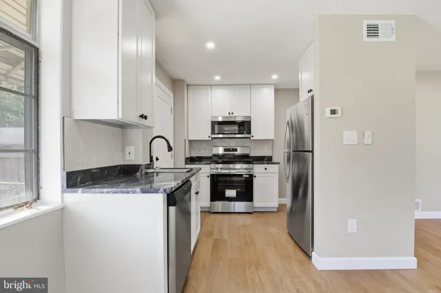 a kitchen with stainless steel appliances granite countertop a refrigerator sink and stove