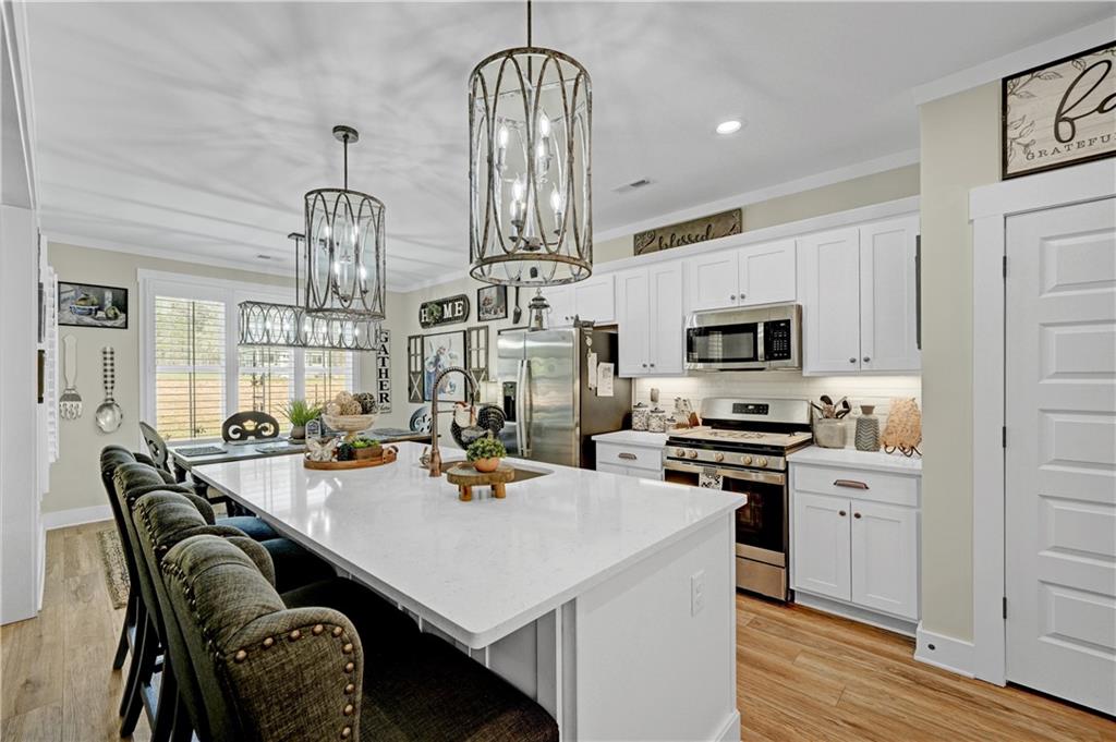 670 Poplar Street Monroe, GA 30655 - Photo 12 of 26 a kitchen with stainless steel appliances a dining table chairs stove and white cabinets