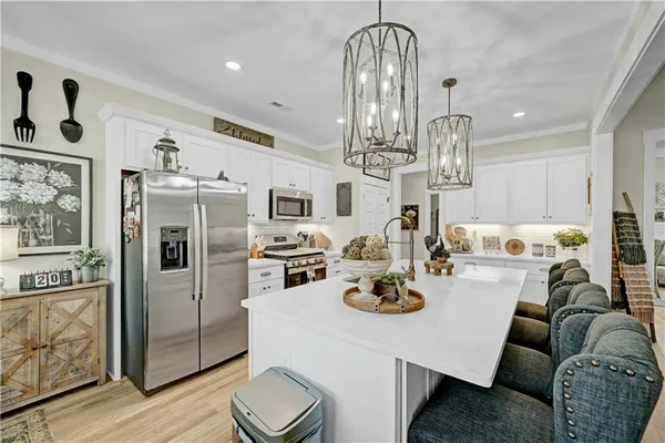 a kitchen with stainless steel appliances kitchen island granite countertop a refrigerator a stove a kitchen island and chairs with wooden floor