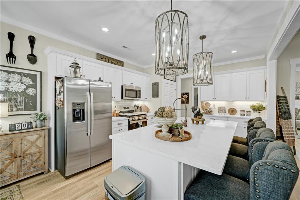 670 Poplar Street Monroe, GA 30655 - Photo 13 of 26 a kitchen with stainless steel appliances kitchen island granite countertop a refrigerator a stove a kitchen island and chairs with wooden floor