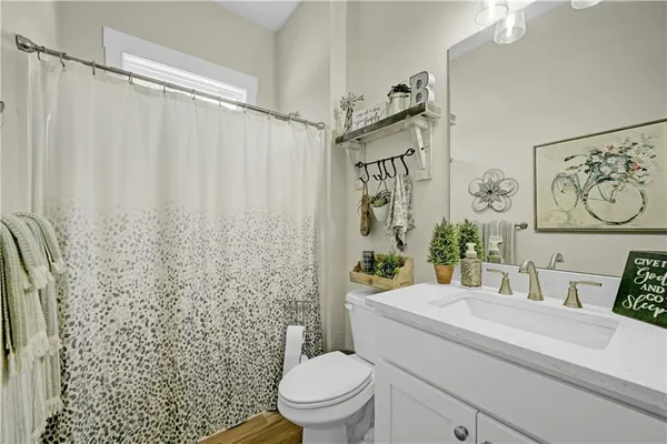 a bathroom with a granite countertop sink a toilet and a shower curtain