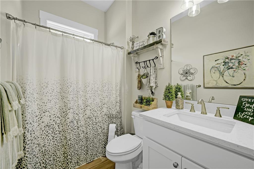 670 Poplar Street Monroe, GA 30655 - Photo 7 of 26 a bathroom with a granite countertop sink a toilet and a shower curtain