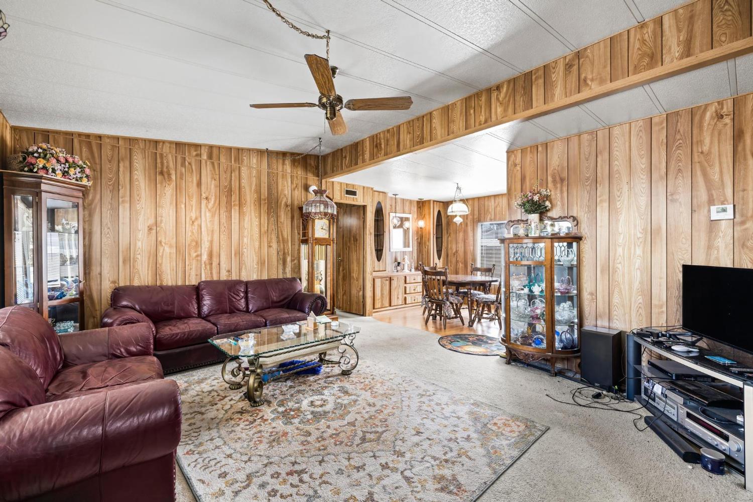 1200 South Carpenter Road, Unit 4 Modesto, CA 95351 - Photo 8 of 31 Living area featuring wood-paneled walls and a wood-finish ceiling fan