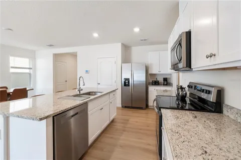 a kitchen with stainless steel appliances granite countertop a sink a stove and a wooden floors