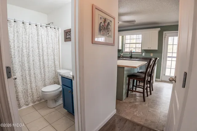 a bathroom with a granite countertop sink and a toilet