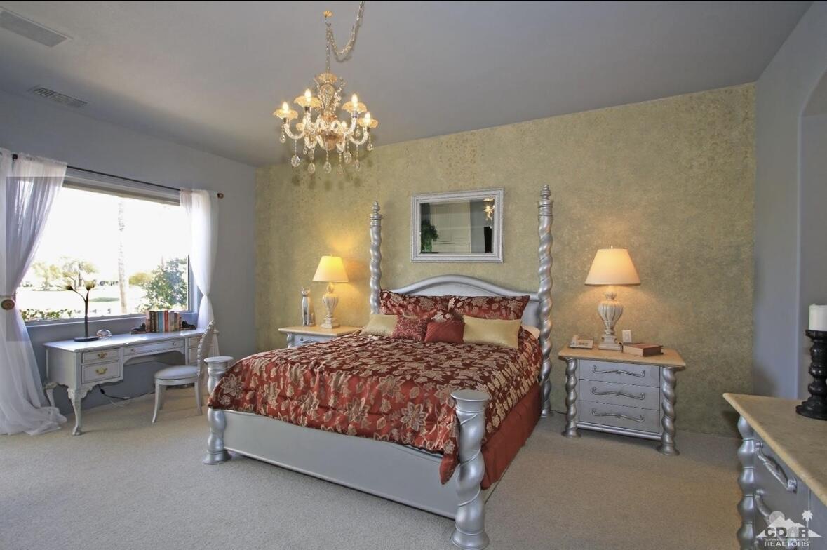 104 Loch Lomond Road Rancho Mirage, CA 92270 - Photo 12 of 27 a bedroom with a bed and a chandelier
