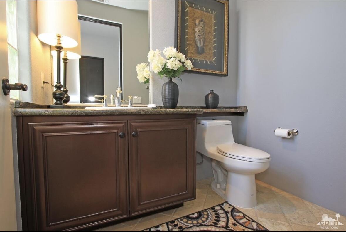 104 Loch Lomond Road Rancho Mirage, CA 92270 - Photo 20 of 27 a bathroom with a toilet a sink and mirror