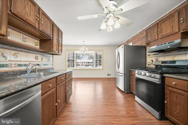a kitchen with stainless steel appliances granite countertop hardwood floor sink stove and granite counter top