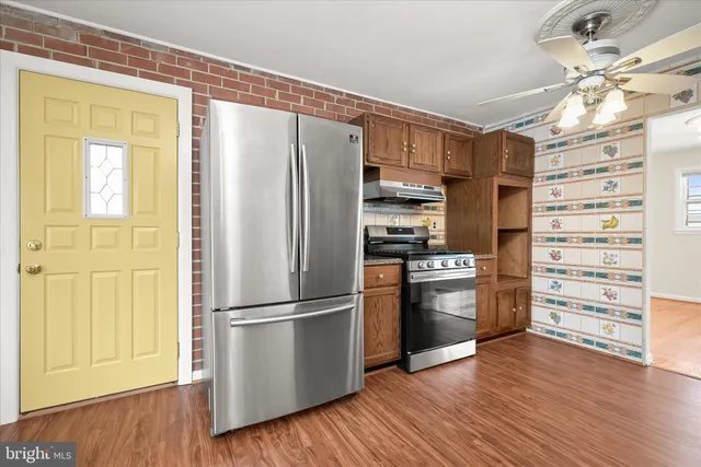 a kitchen with stainless steel appliances a refrigerator and a wooden floor