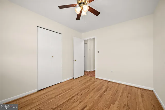 an empty room with wooden floor chandelier fan and closet area