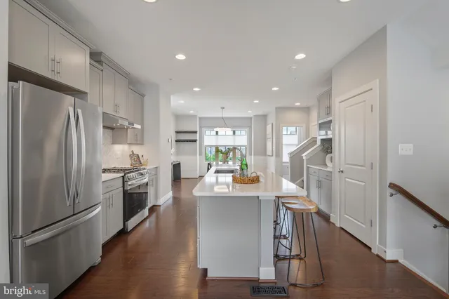 a kitchen with kitchen island a counter top space a refrigerator and a view of living room