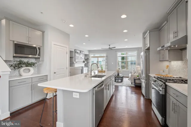 a large kitchen with stainless steel appliances a sink a stove and cabinets