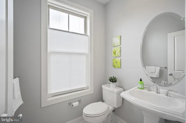 a bathroom with a toilet a sink a mirror and a window