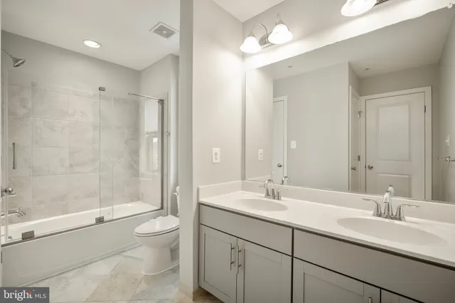 a bathroom with a double vanity sink toilet mirror and shower