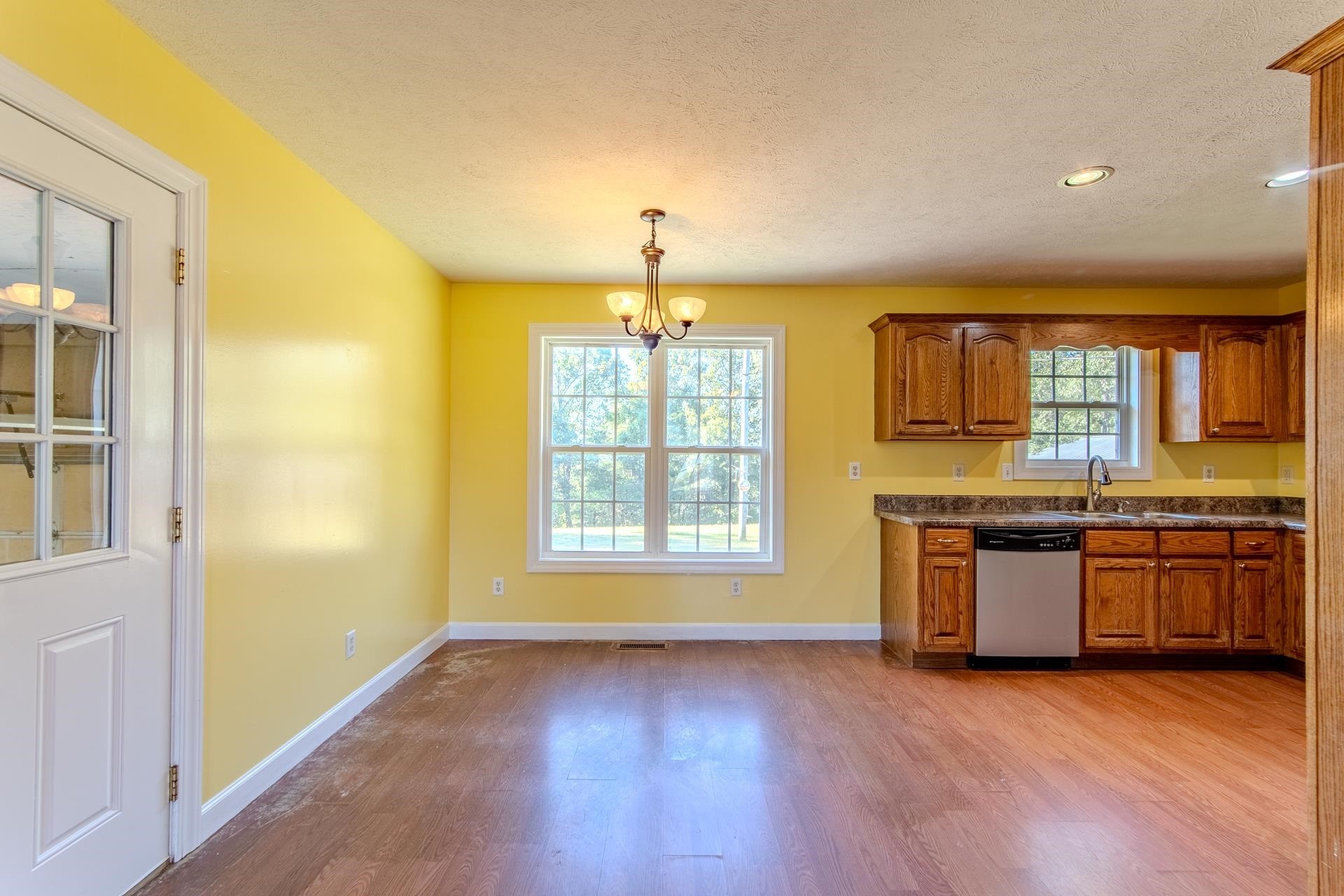 150 Hollis Way Adamsville, TN 38310 - Photo 15 of 37 an empty room with a kitchen and wooden floor