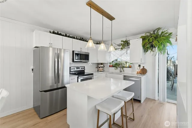 a kitchen with stainless steel appliances a refrigerator a stove a sink and a potted plant