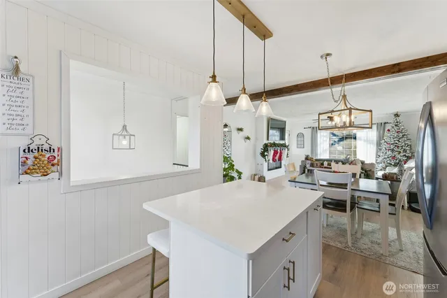 a kitchen with stainless steel appliances a stove top oven a sink dishwasher a refrigerator and white cabinets with wooden floor